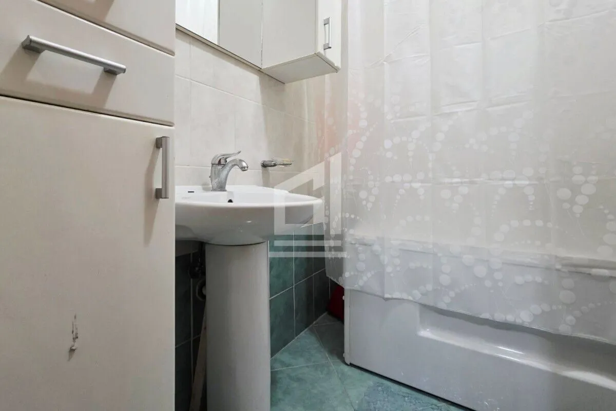 Small bathroom with a sink and a bathtub with a curtain.