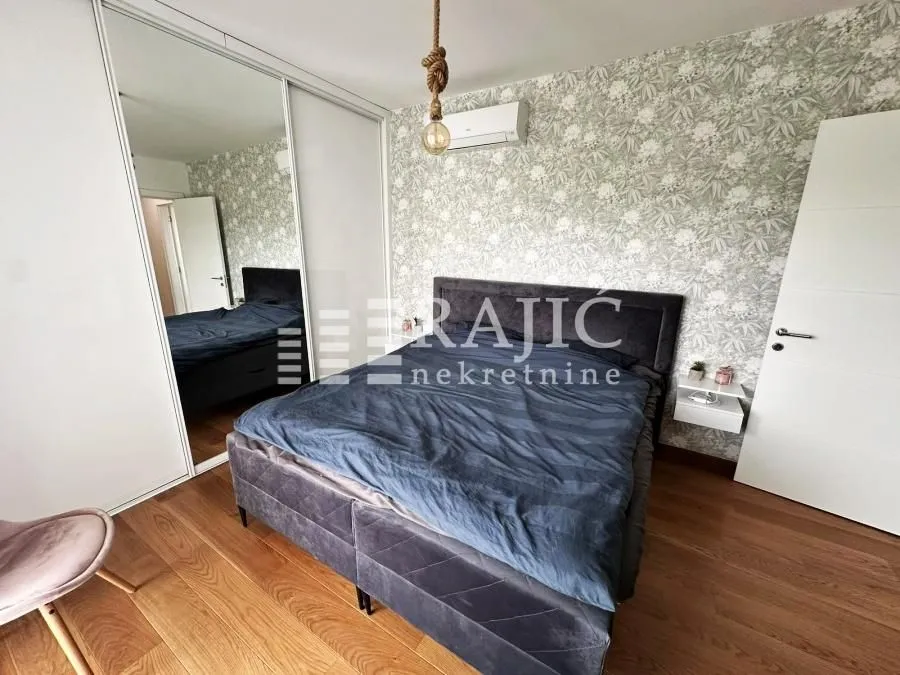 Furnished bedroom with a double bed and a mirrored built-in wardrobe.