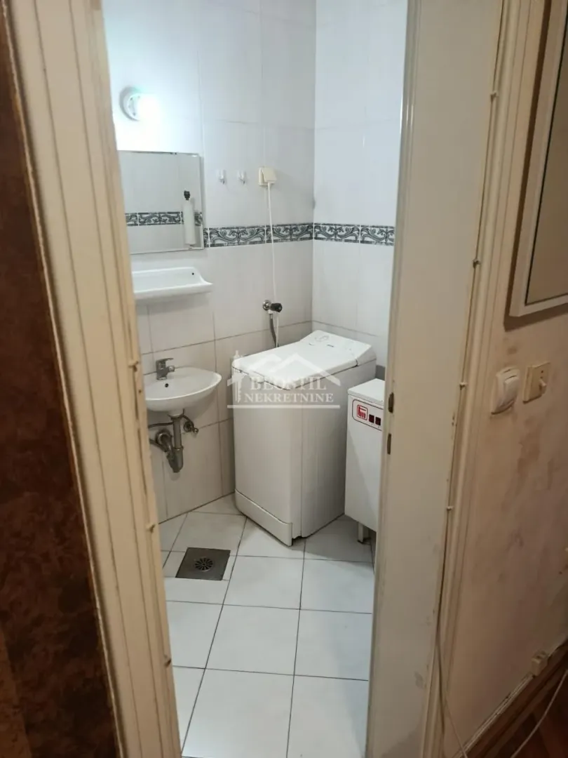 View of the bathroom with a washbasin and washing machine through an open door.