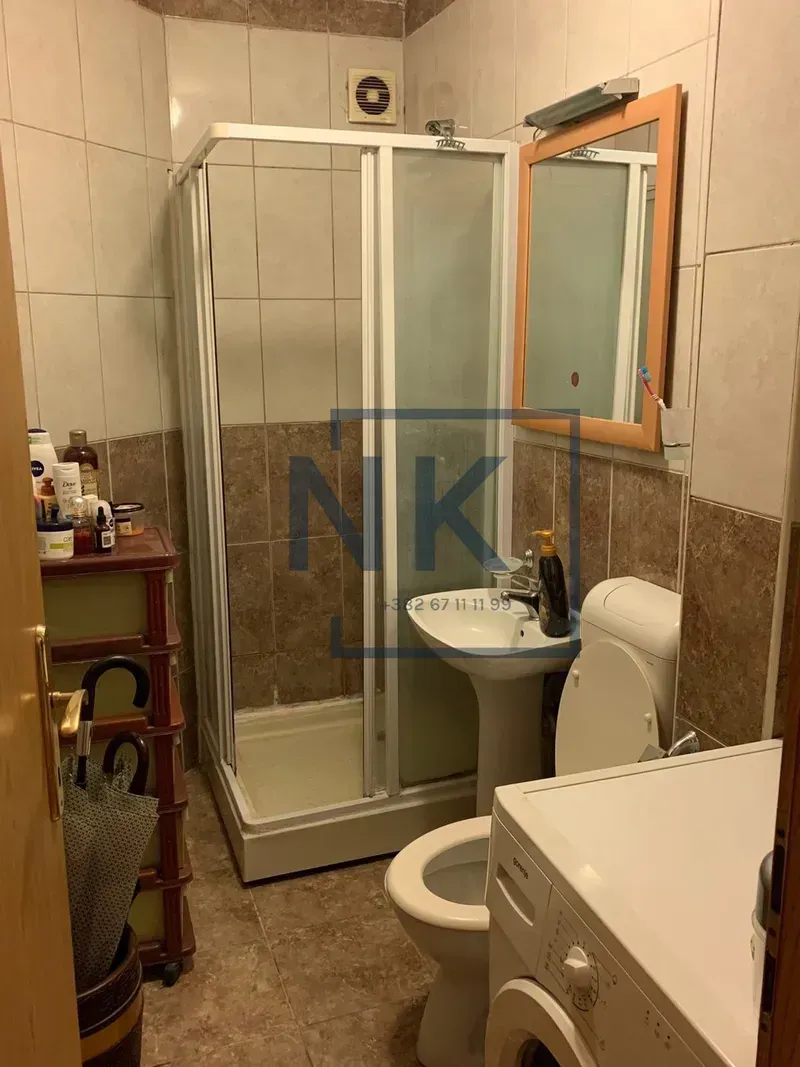 Smaller bathroom with a shower cabin, washbasin, toilet, and washing machine.