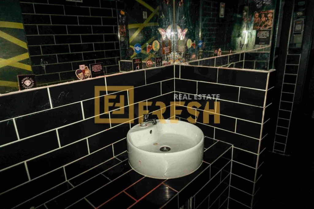 Bathroom with a washbasin and black tiles.