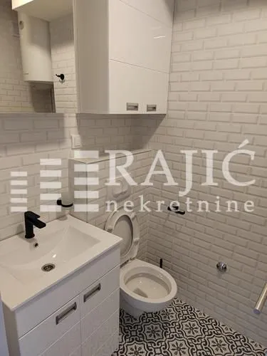 Modernly equipped bathroom with white tiles and sanitary ware.