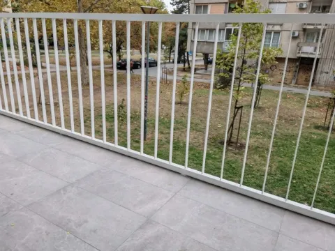 Pogled sa popločane terase sa belom ogradom na zelenilo i ulicu. - image 7