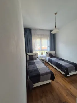 Bedroom with two single beds and wooden flooring. - image 7