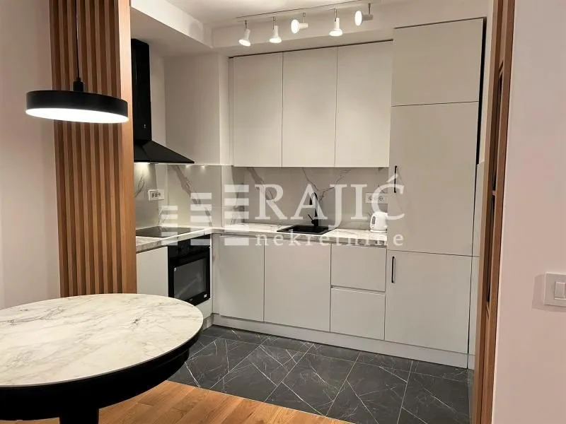 Modern kitchen with white units and a dining table.