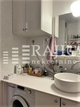 Small bathroom with a basin, washing machine, and white cabinets. - image 8