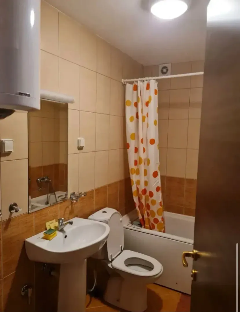 Smaller bathroom with a washbasin, toilet, bathtub, and mirror.