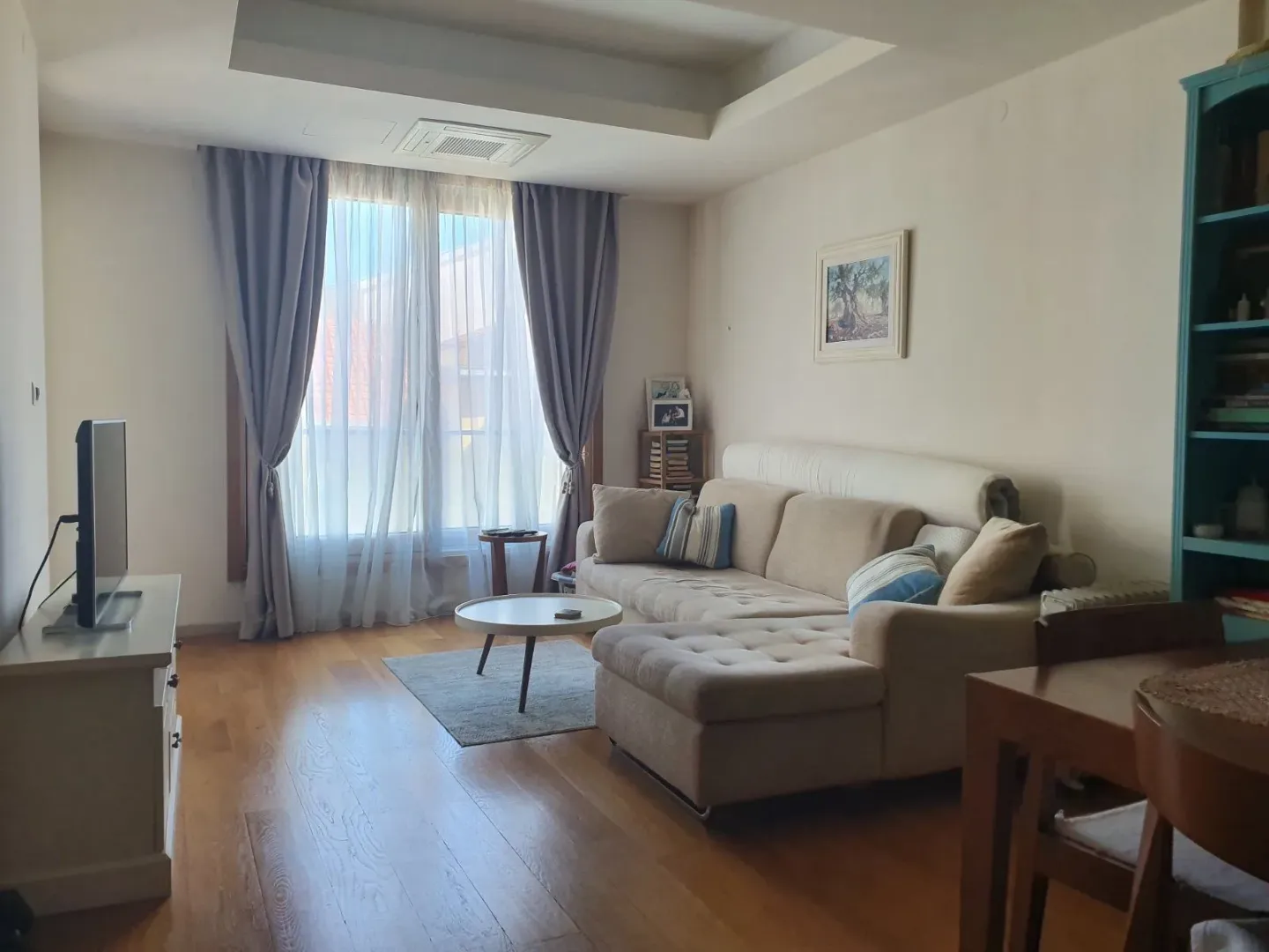 Prostrana dnevna soba sa garniturom za sjedenje i TV komodom.