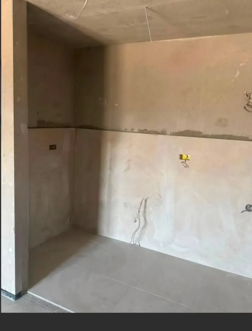 View of a section of a room under construction with plastered walls.