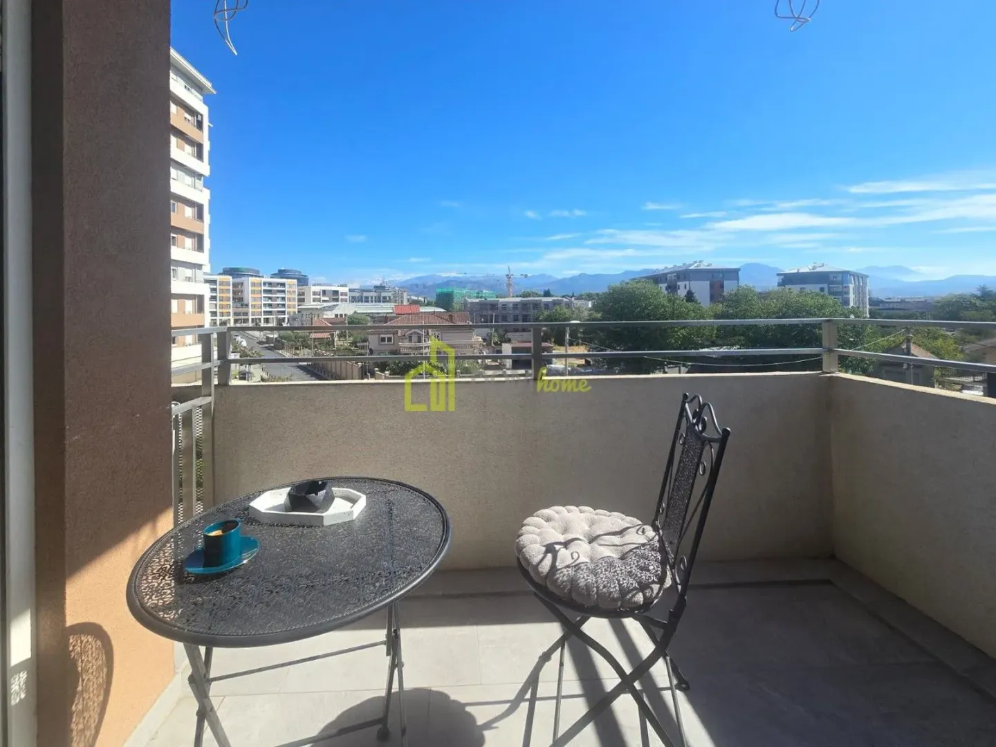 Small balcony with a small table and a chair and a city view.