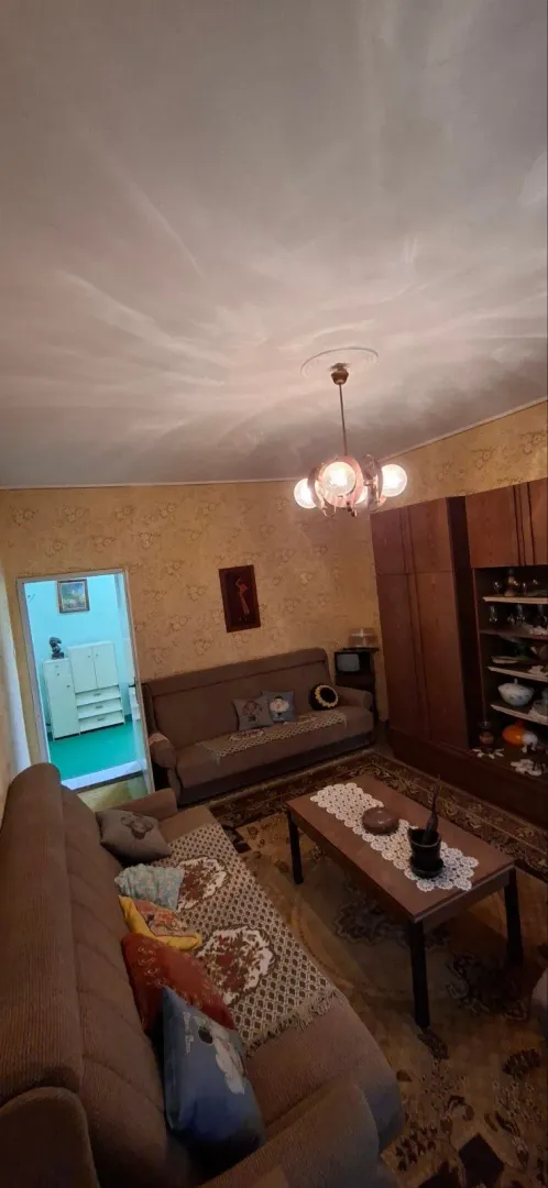 Dnevna soba sa garniturom za sedenje, velikim ormanom i lusterom.