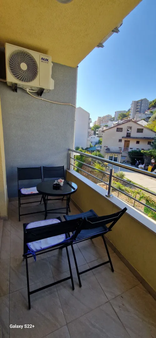 Small furnished balcony with a table and chairs.