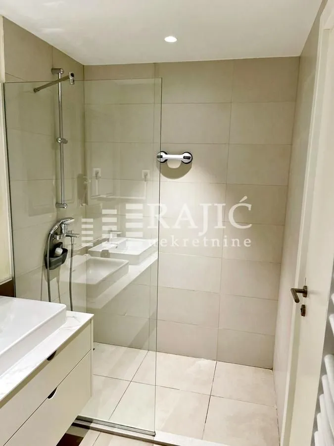 Modern bathroom with a walk-in shower and washbasin.