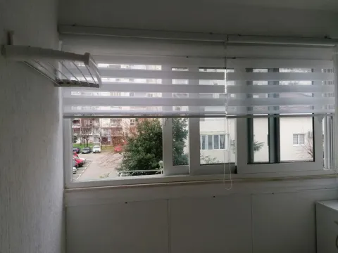 Enclosed balcony with blinds and a view of the parking lot and buildings. - image 7