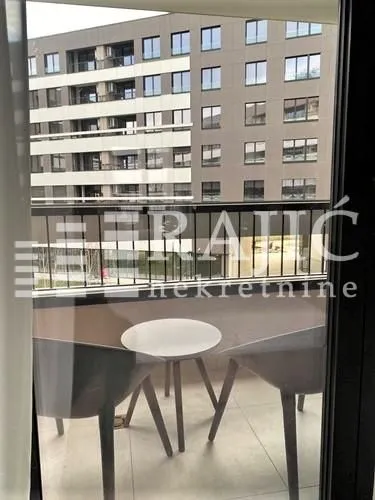 Furnished balcony with seating set and a view of neighboring buildings.