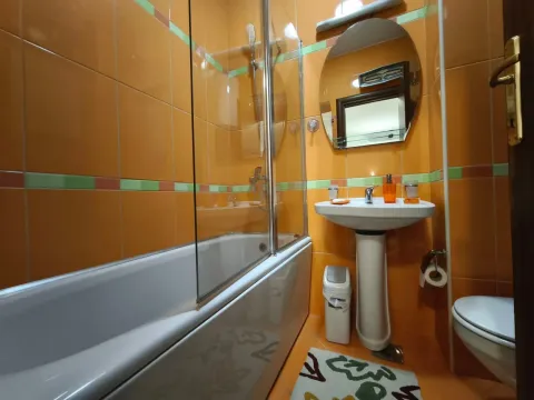 Kupatilo obloženo narandžastim pločicama sa kadom, umivaonikom i WC šoljom. - image 17