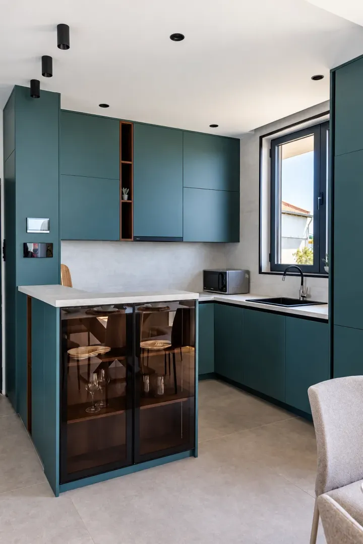 Modern kitchen with dark green cabinets and a built-in kitchen island with glass display doors.