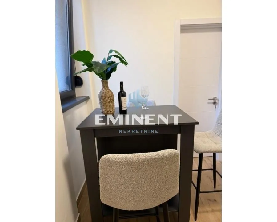 Small dining table with bar stools and a bottle of wine.