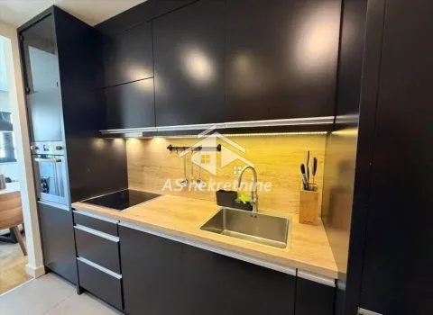 Modern kitchen with black units and a wooden countertop. - image 8