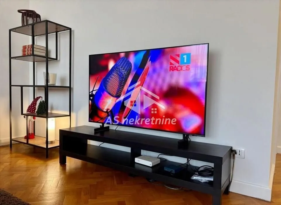 Living room with a television on a stand and a metal shelving unit.