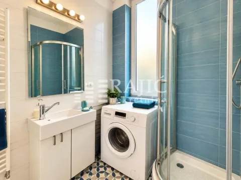 Tidy bathroom with a washbasin, washing machine, and shower cabin. - image 6