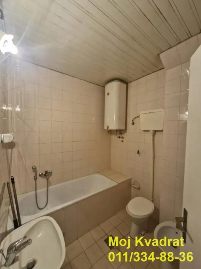 Smaller bathroom with a bathtub, toilet, sink, and water heater.
