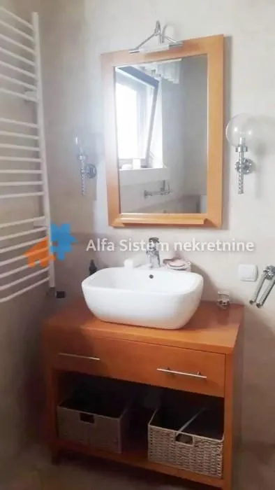 Bathroom with a washbasin, wooden vanity unit and a mirror.