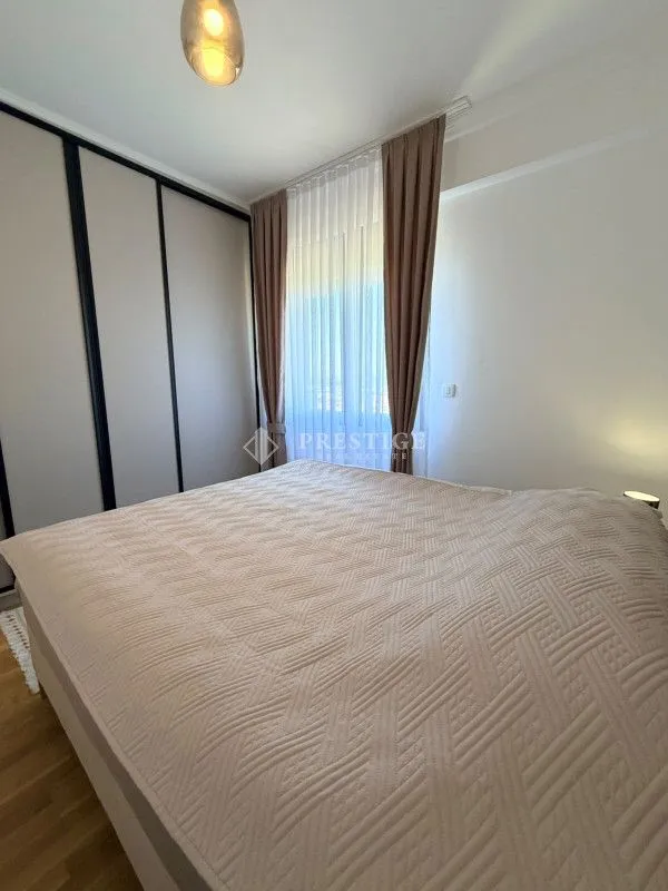 Uređena spavaća soba sa velikim bračnim krevetom, garderoberom i prozorom sa zavjesama.