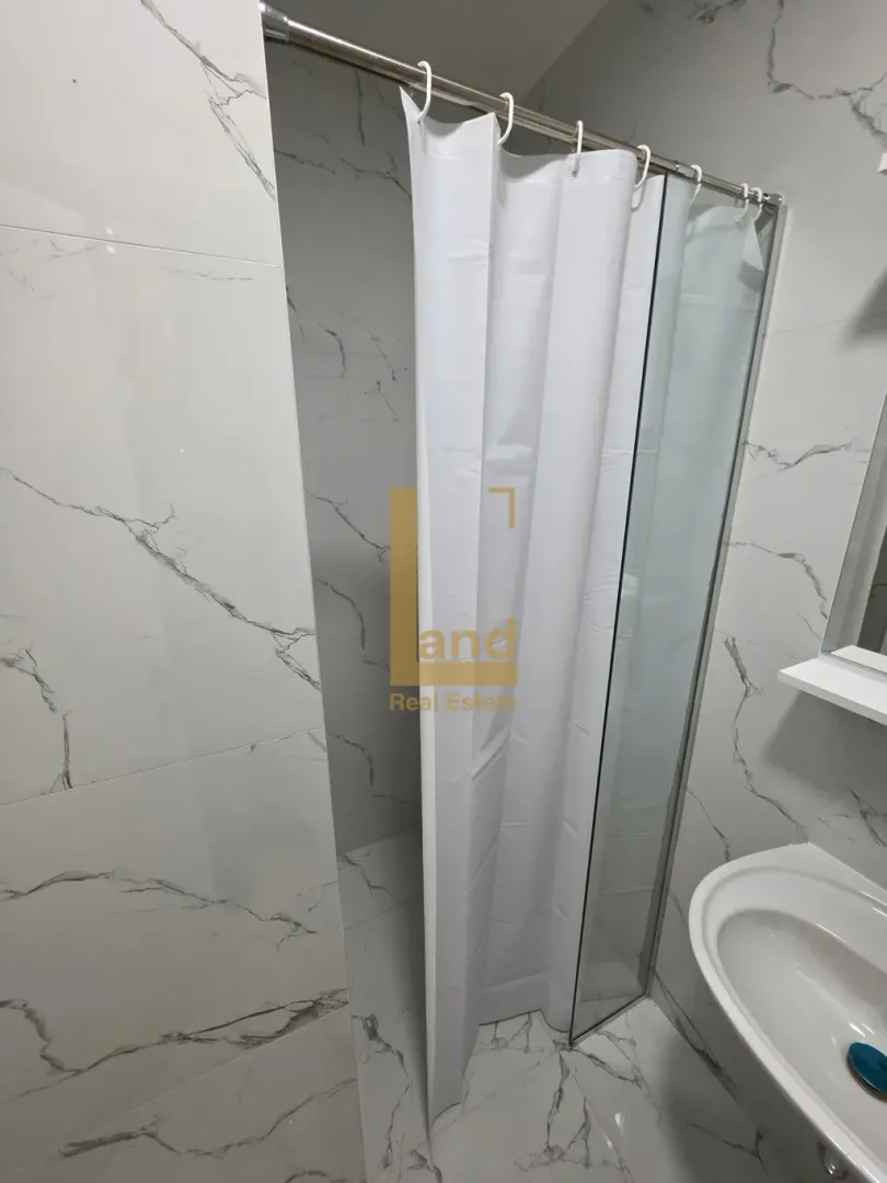 Modern bathroom with a shower cabin and marble tiles.