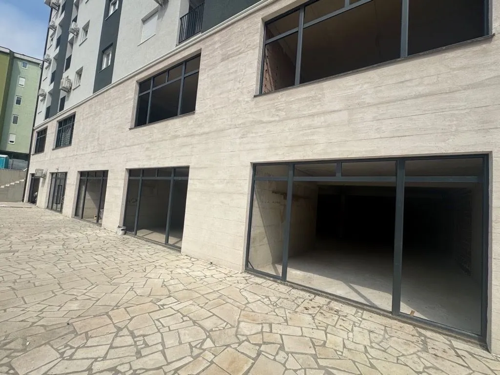Exterior view of a building with ground floor commercial spaces and a paved courtyard.
