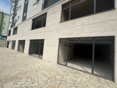 Exterior view of a building with ground floor commercial spaces and a paved courtyard. - image 7