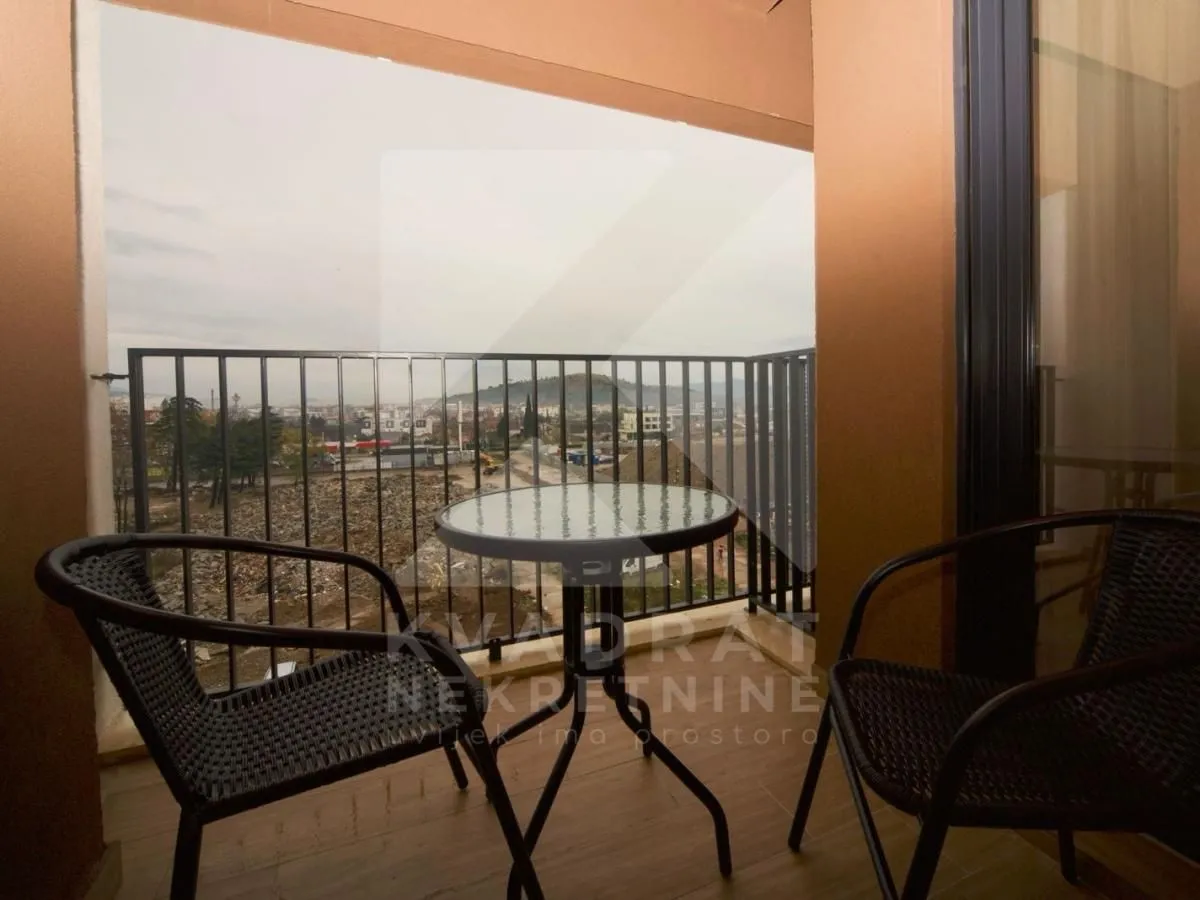 Natkriveni balkon sa stočićem, stolicama i pogledom na okolinu.