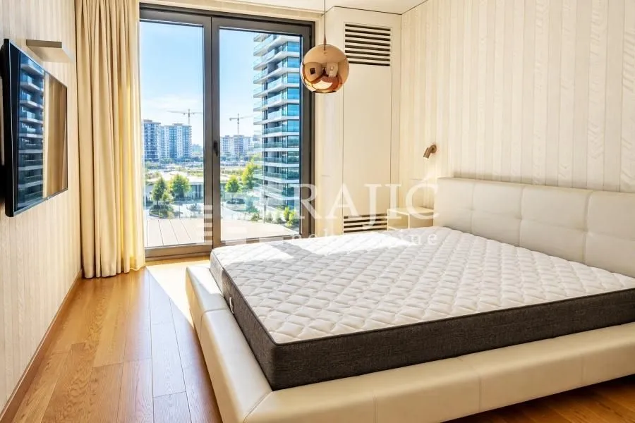Modern bedroom with a double bed, wooden floor, and access to the terrace.