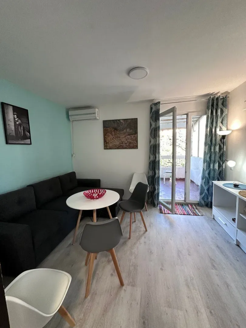 Living room with sofa, dining table, and access to the terrace.