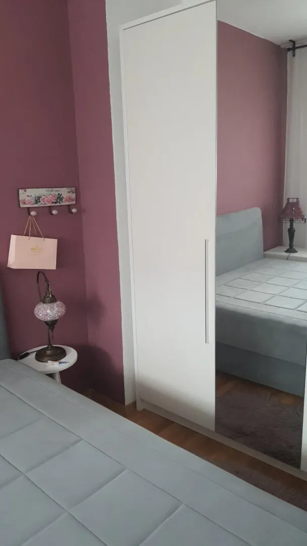 Bedroom with a white wardrobe and a grey bed.