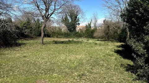 Pogled na prostrani plac okružen zelenilom i drvećem. - image 2