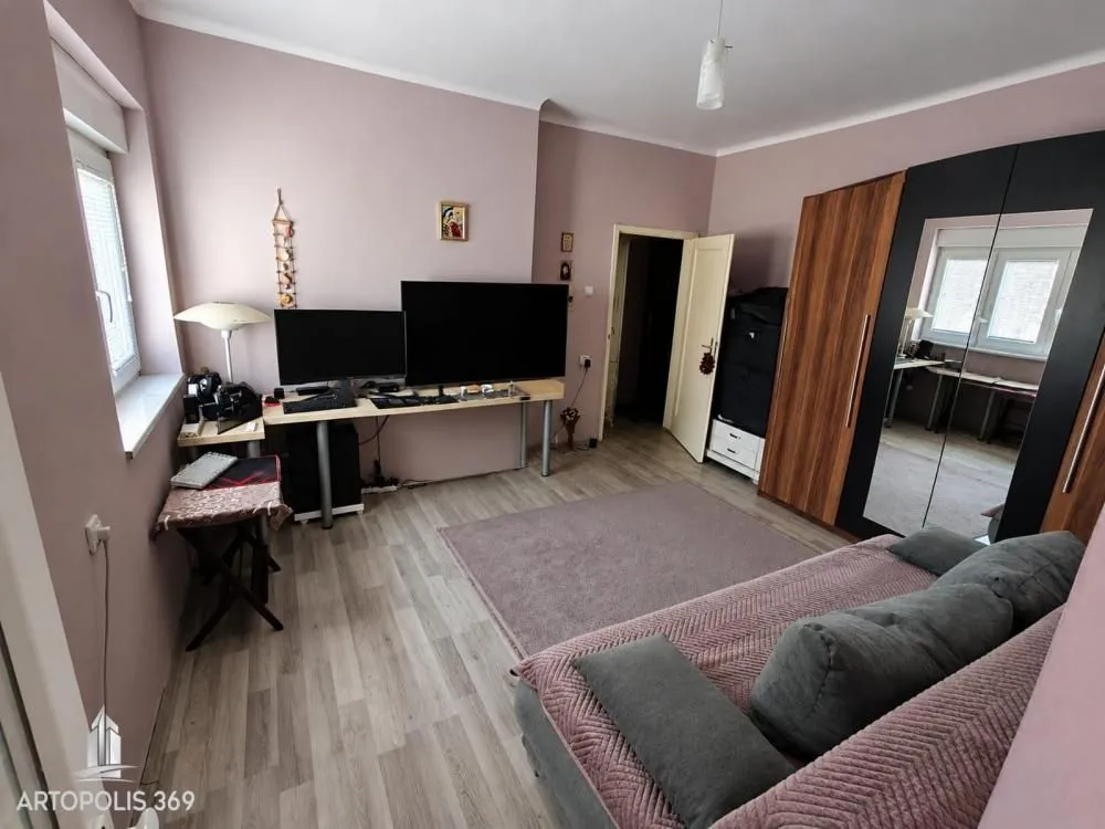 Nameštena spavaća soba sa krevetom, radnim stolom i ormanom.