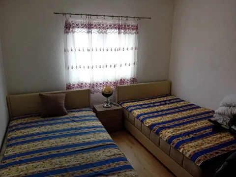 Spavaća soba sa dva kreveta i noćnim stočićem pored prozora. - image 7