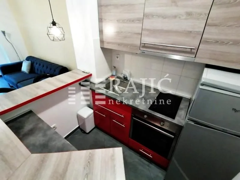 Small kitchen with red cabinets and a view of the living room.