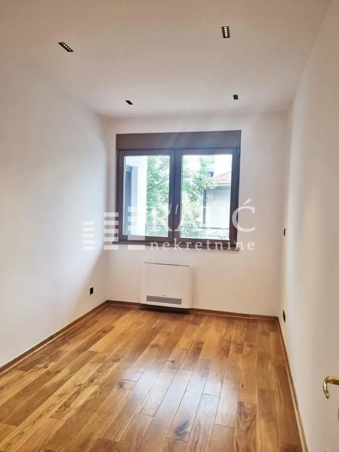 Empty room with wooden flooring and a window.