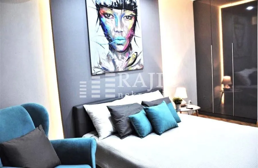 Modern bedroom with a double bed, blue armchair, and an art painting on the wall.