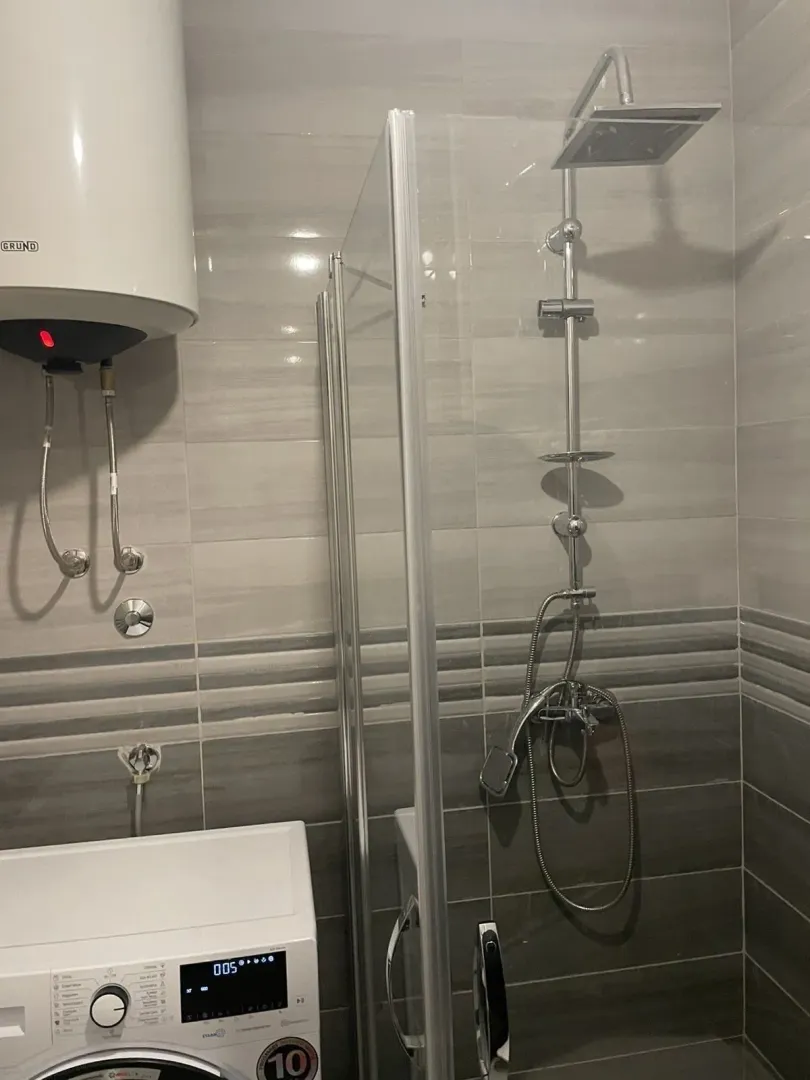 Moderno kupatilo sa tuš kabinom i veš mašinom.