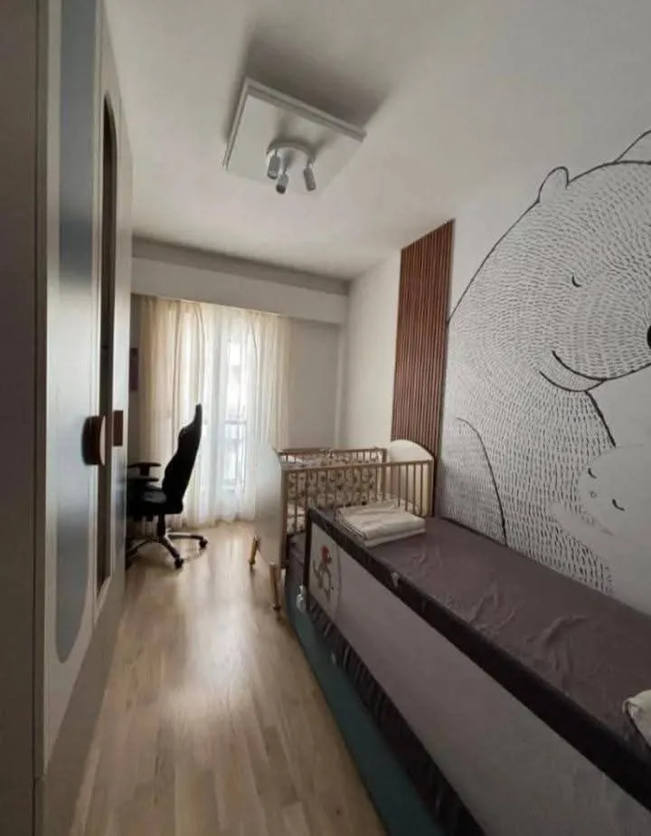 Dječja spavaća soba sa krevetom, krevetcem i garderoberom.