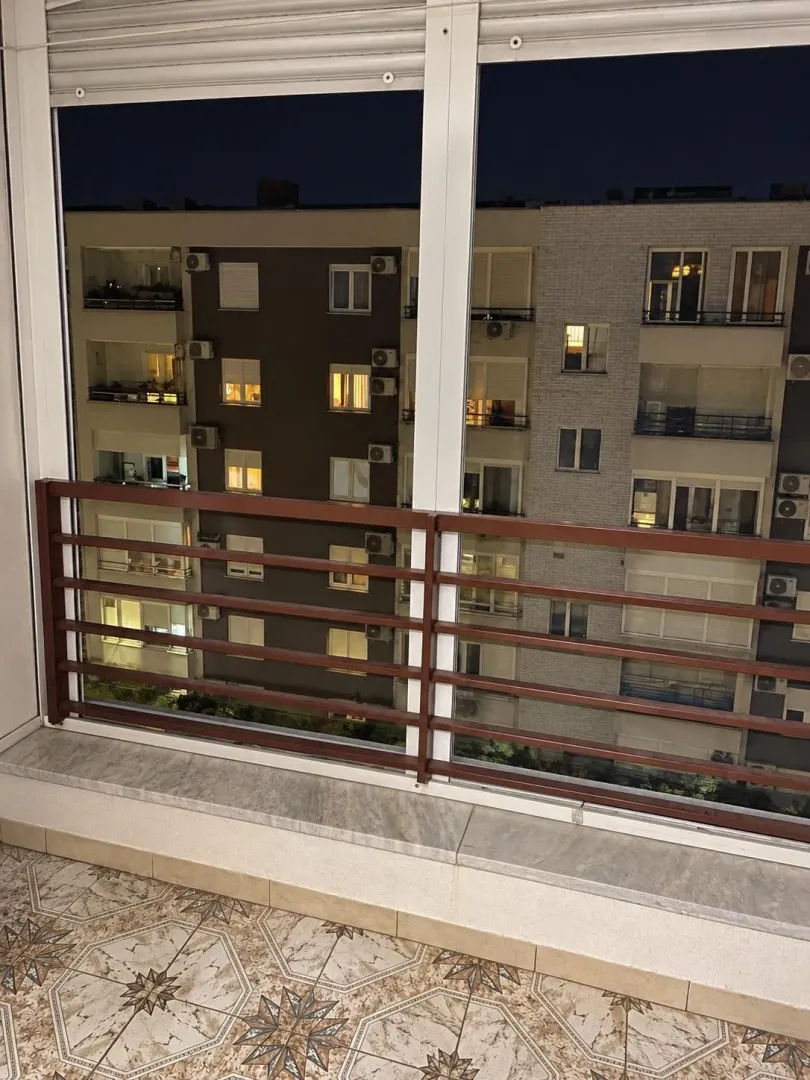 Pogled sa zastakljene terase na okolne stambene zgrade noću.