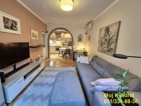 Dnevna soba sa garniturom, TV-om i pogledom na trpezariju i kuhinju kroz luk. - image 2
