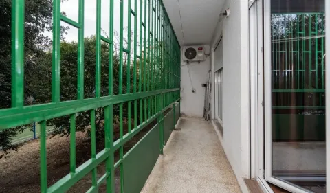 Long balcony with a green railing and an outdoor air conditioning unit. - image 11