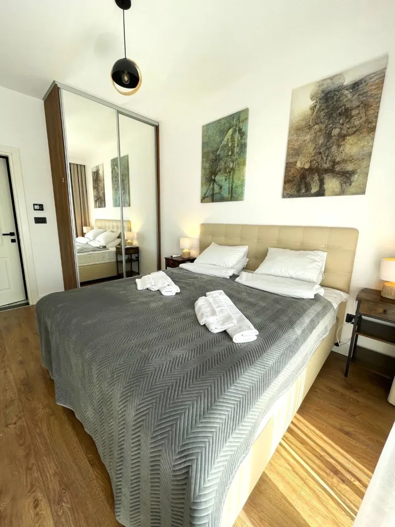 Furnished bedroom with a double bed, mirrored wardrobe, and wall art.