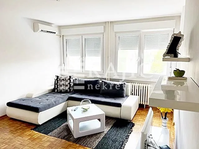 Living room with a sectional sofa, coffee table, and air conditioning unit.