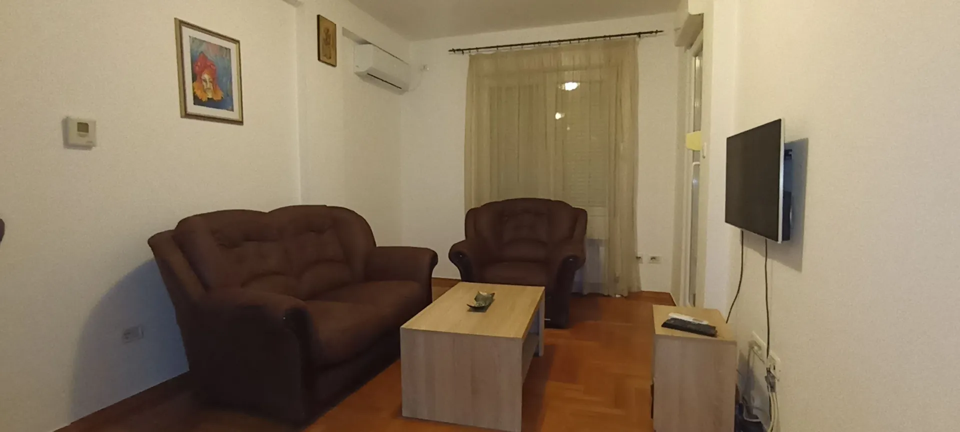 A living room featuring a brown sofa set, a coffee table, and a wall-mounted TV.