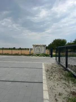 View of the paved parking area with a fence and surrounding landscape. - image 5